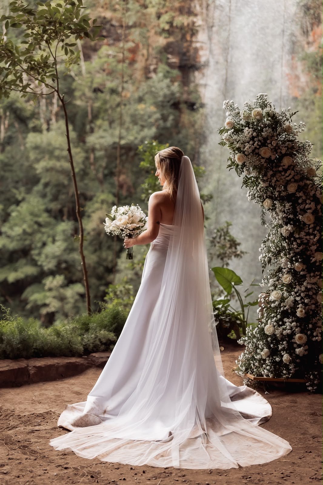 Noiva de véu longo em frente a uma cachoeira